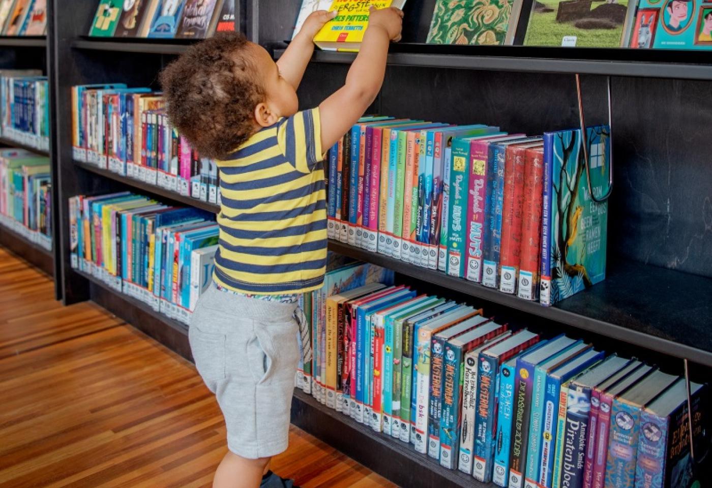 Een kind kiest zelf een boek in de jeugdbib van Muntpunt